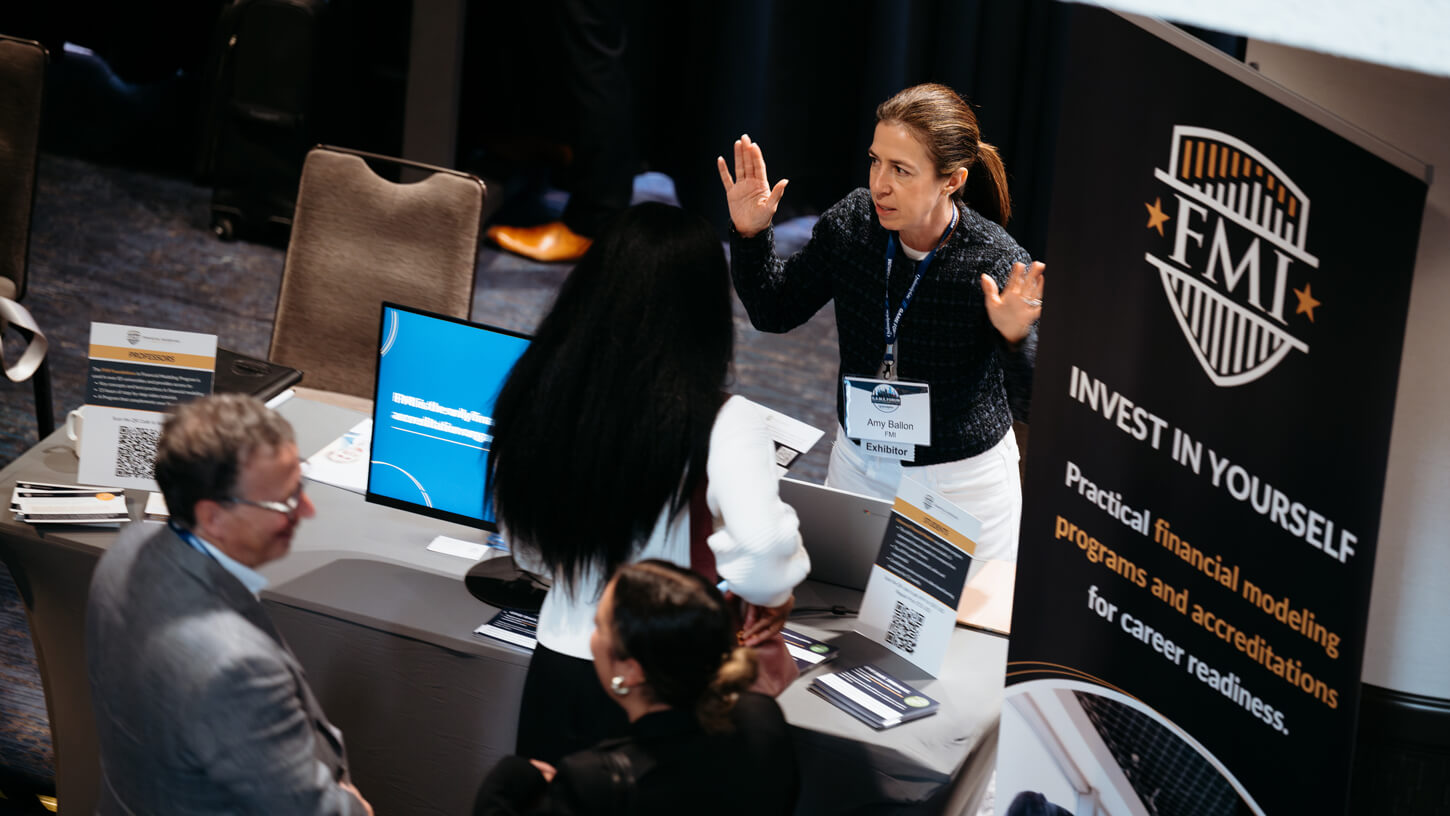 Amy Ballon from FMI explains credentialing options to a group of students around a branded exhibit booth.