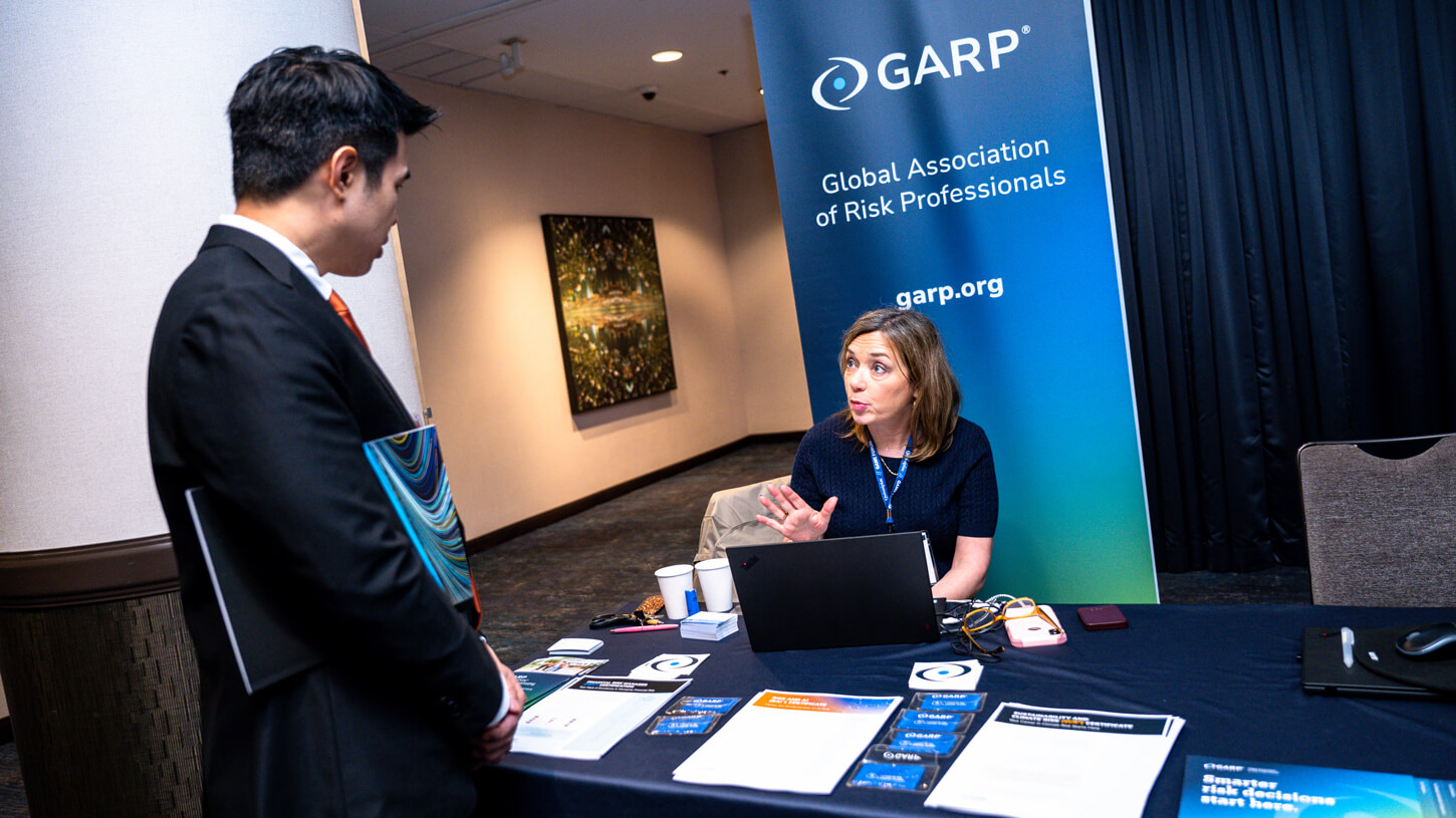 A GARP representative explains risk management pathways to a student in professional attire.