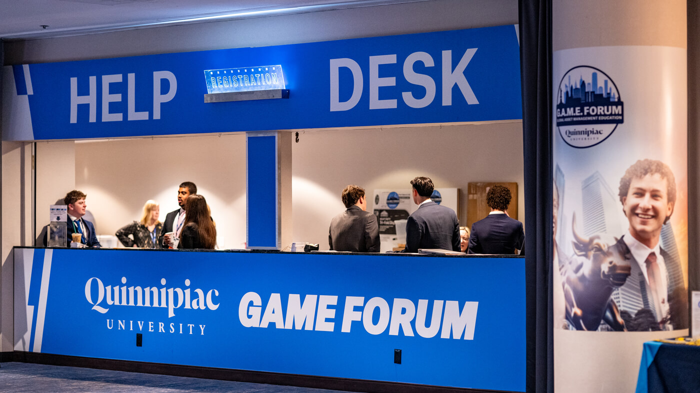 Attendees interact with staff at the Quinnipiac GAME Forum help and registration desk.