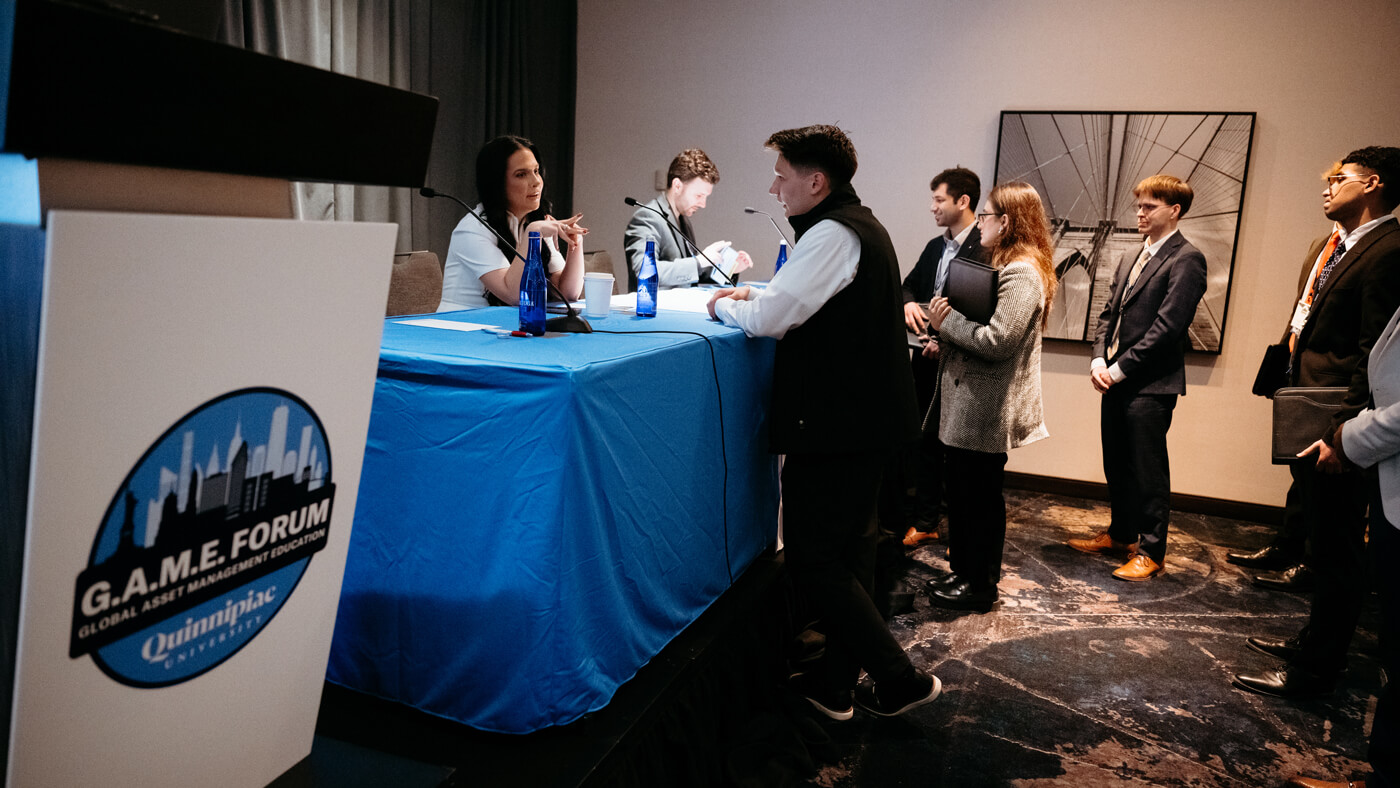 Students line up to speak with panelists after a session at the Quinnipiac GAME Forum, engaging in one-on-one conversation at the edge of the stage.